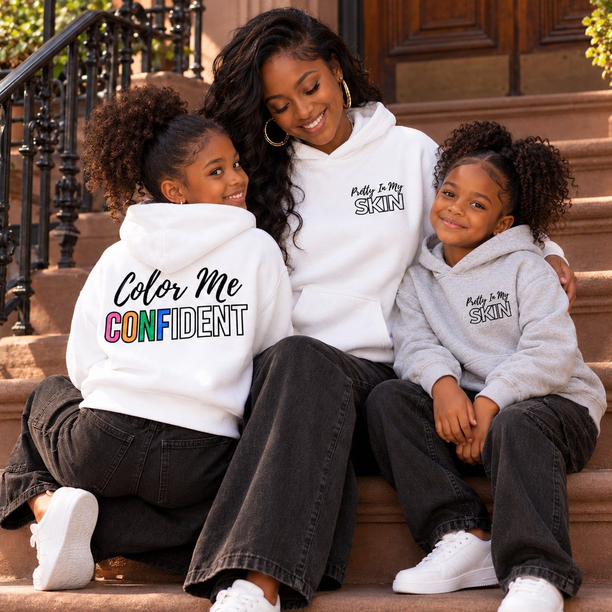 Mother with her two daughters in matching Color Me Confident hoodies on a Brooklyn stoop